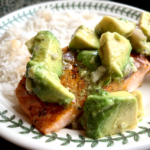 baked salmon on plate next to rice with avocado on top