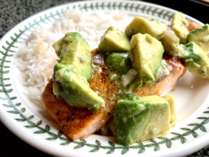 baked salmon on plate next to rice with avocado on top